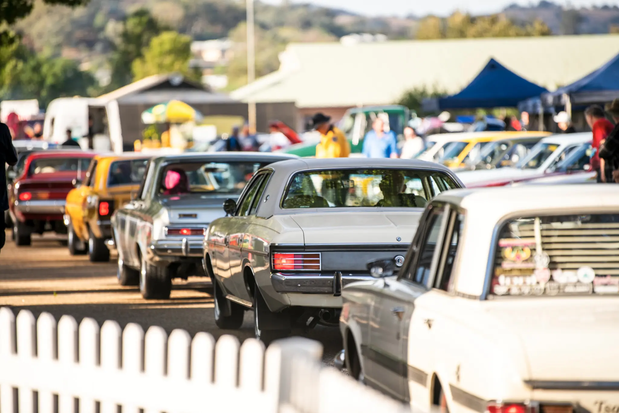 A line of classic Chrysler vehicles moving through the event grounds