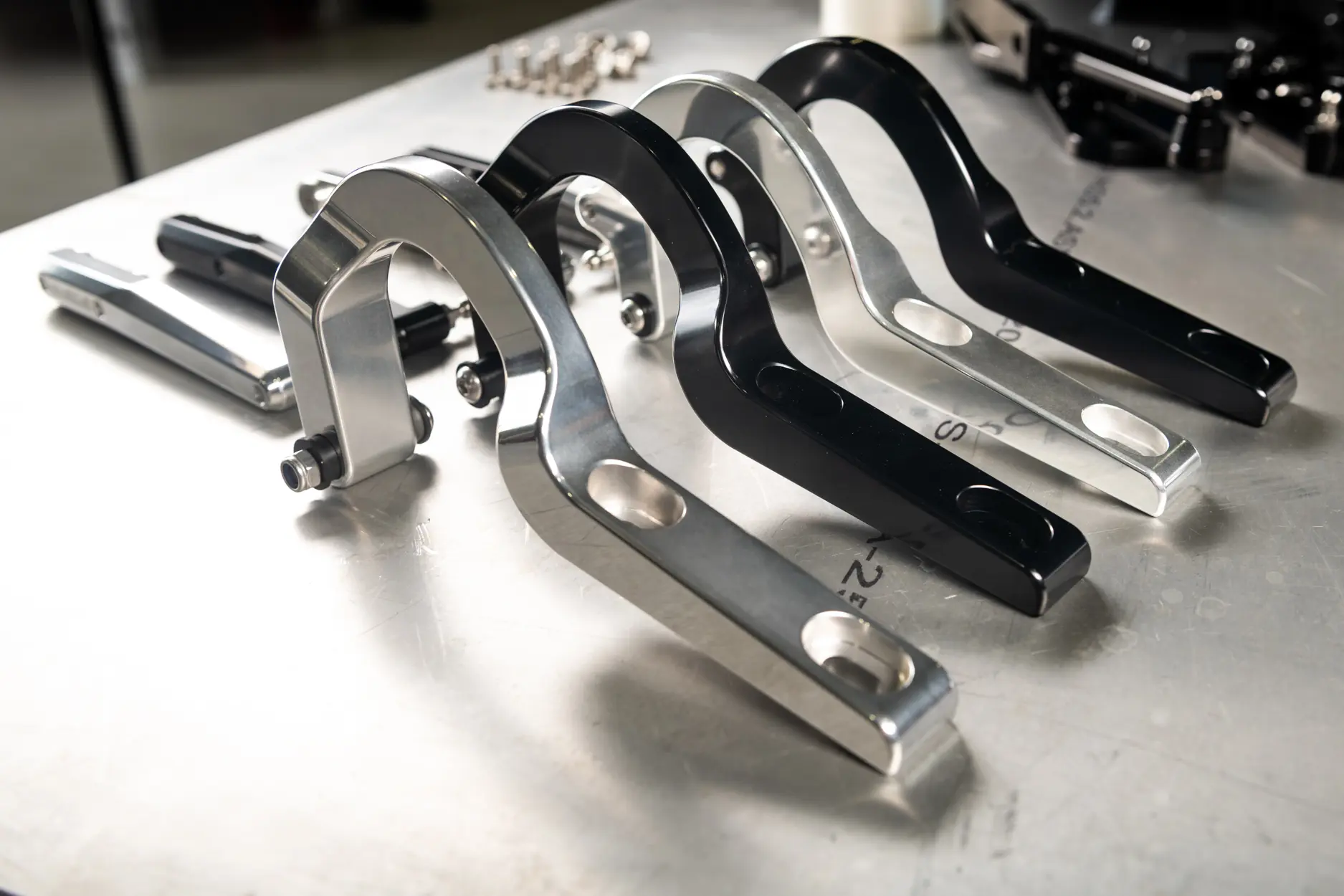 Precision-machined OC Billet automotive brackets arranged on a workbench