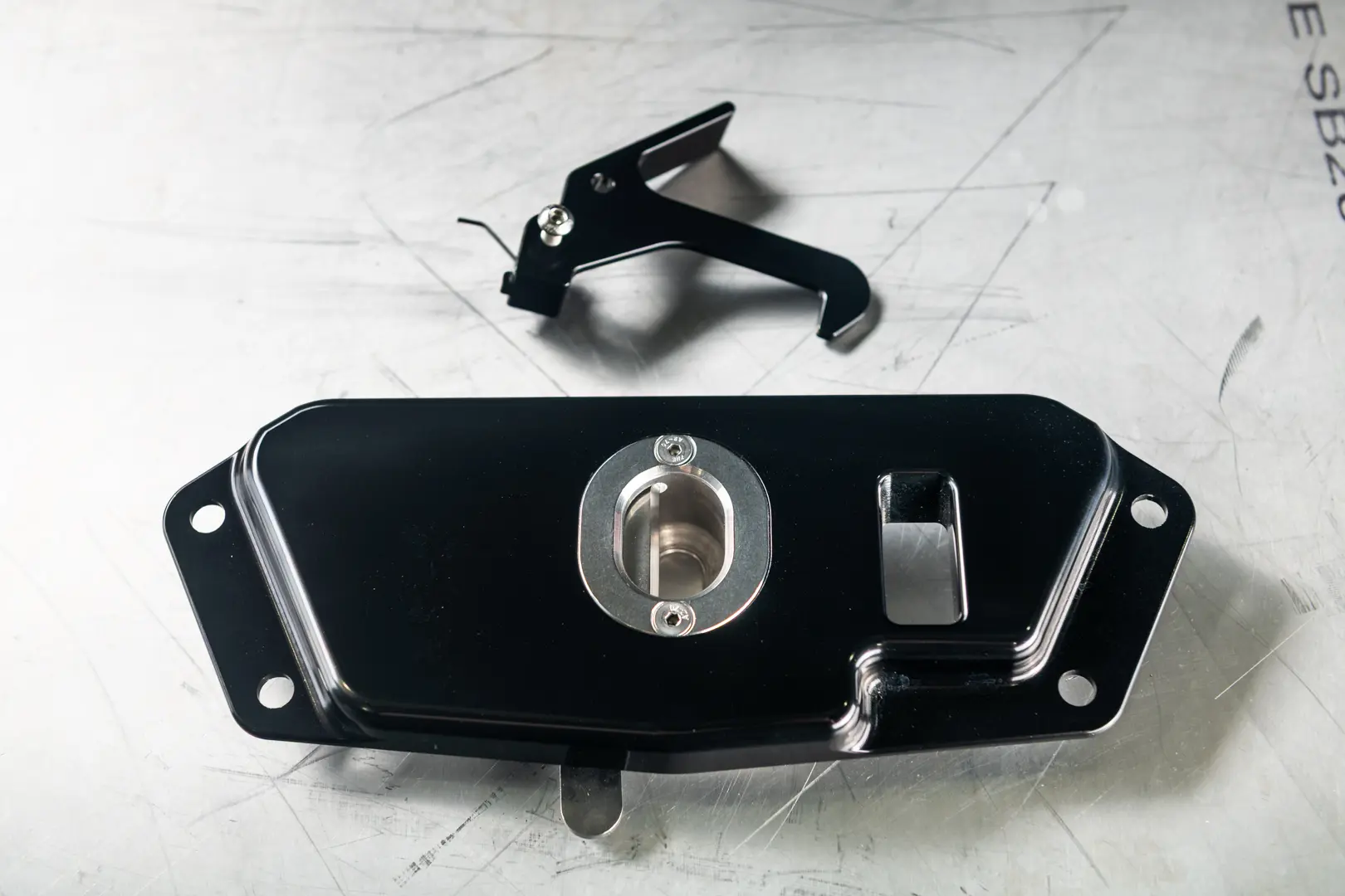 Black machined automotive latch component on a metal table