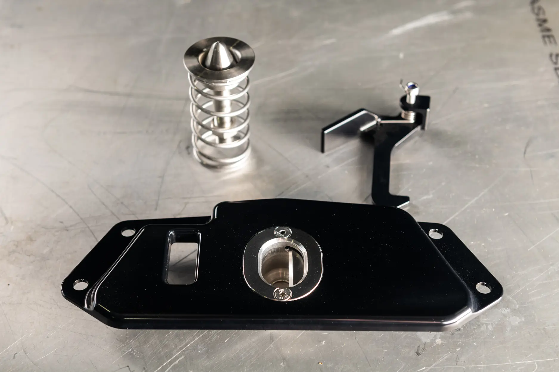 Machined latch components arranged on a metal workbench