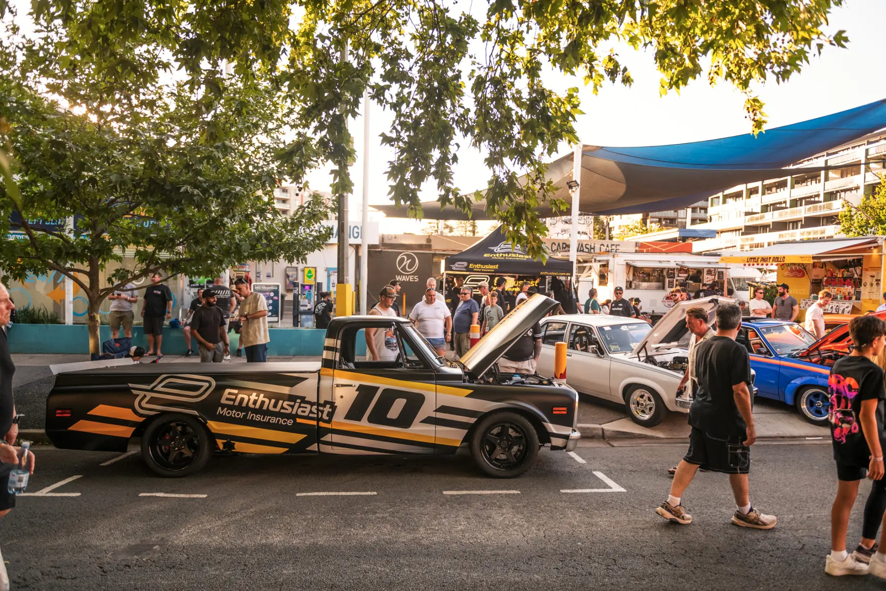 Enthusiasts gathered around modified cars at a street event