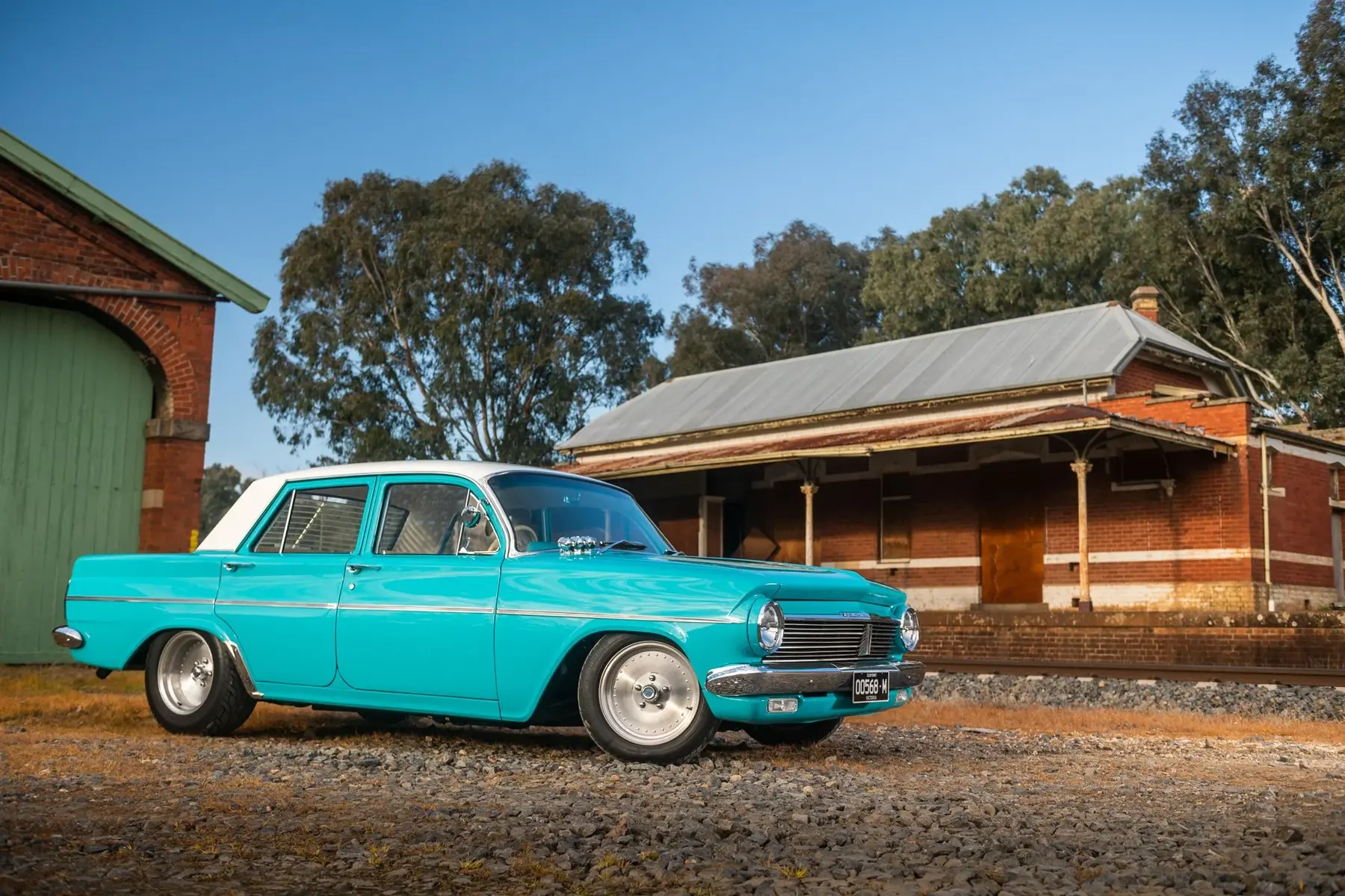 Blue classic Holden wagon photographed beside a railway building